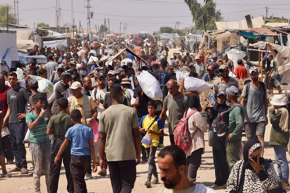 فلسطينيون يحملون مساعدات إنسانية أثناء سيرهم في منطقة المواصي في رفح جنوبي قطاع غزة - 30 تموز/يوليو 2025 (أ ف ب)