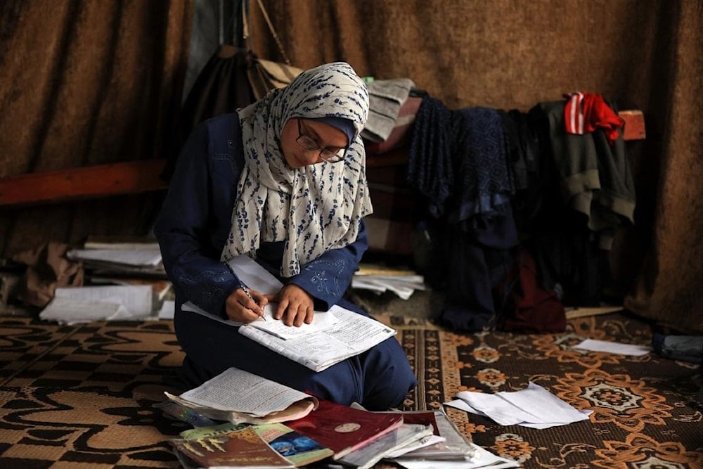 طالبة فلسطينية تدوّن ملاحظات على كتب وأوراق وجدتها بين الأنقاض