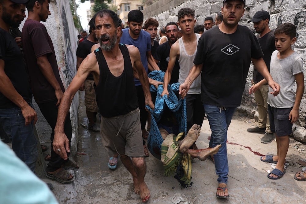فلسطينيون يحملون جثمان رجل فلسطيني ارتقى في غارة إسرائيلية غربي مدينة غزة - 12 آب/أغسطس 2025 (أ ف ب)