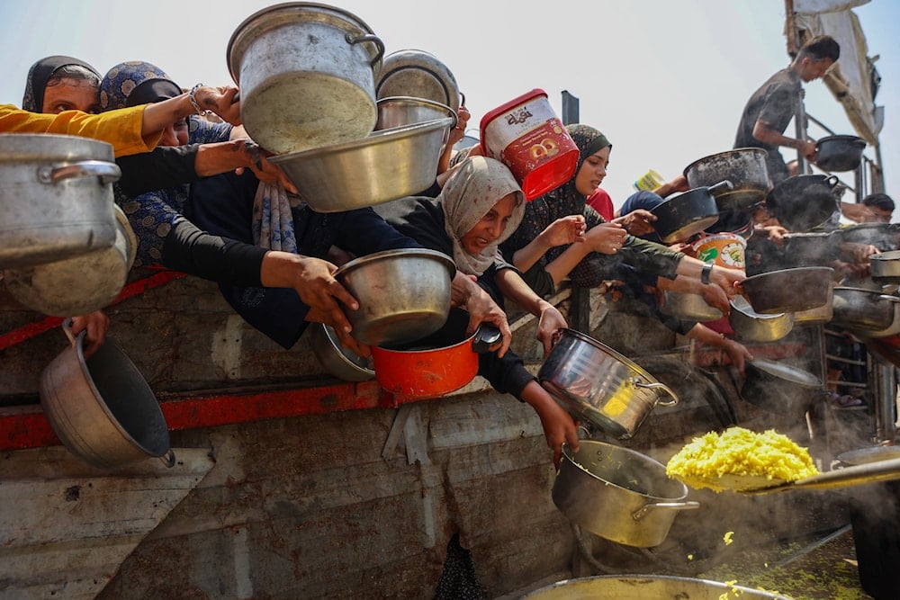 فلسطينيون يتجمعون لتلقي وجبات مطبوخة من مركز توزيع الأغذية في مدينة غزة - 13 آب/أغسطس 2025 (أ ف ب)
