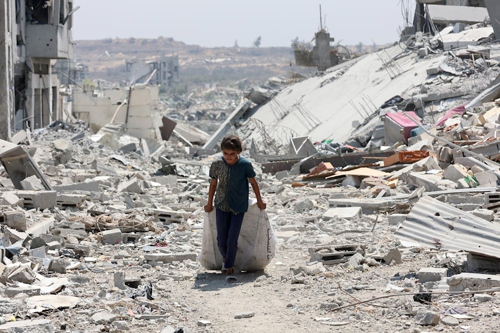 فتاة تنقل أغراضاً بين منازل دمرها القصف الإسرائيلي على في حي التفاح في مدينة غزة (AFP)