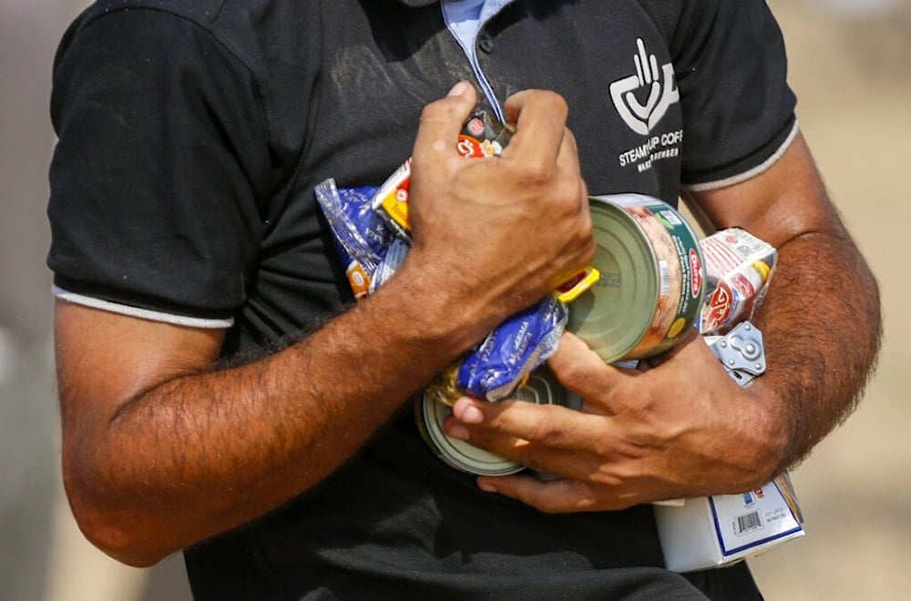 شخص يحصل على مساعدات إنسانية تم إنزالها بالمظلات في دير البلح وسط قطاع غزة (AFP)