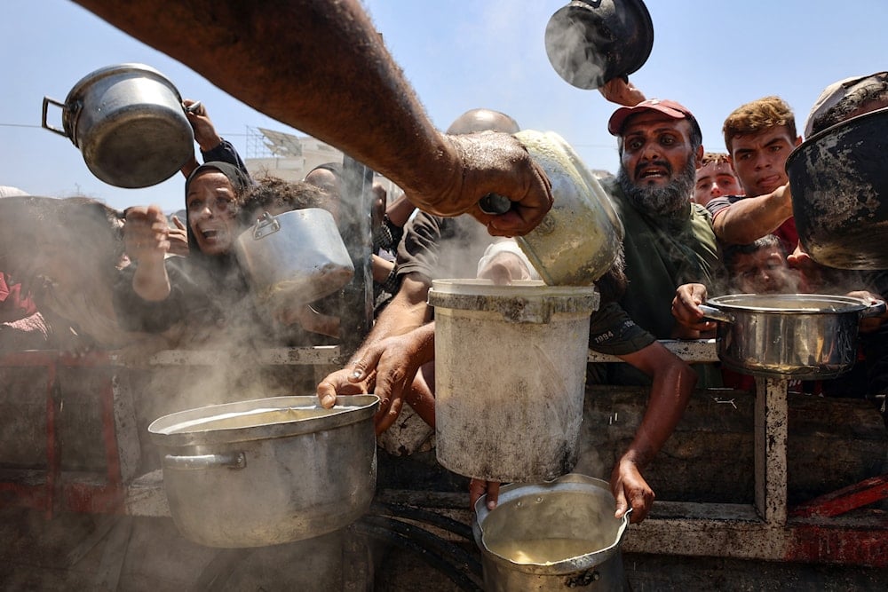 أشخاص يحاولون الحصول على طعام من أحد نقاط التوزيع في قطاع غزة (AFP)
