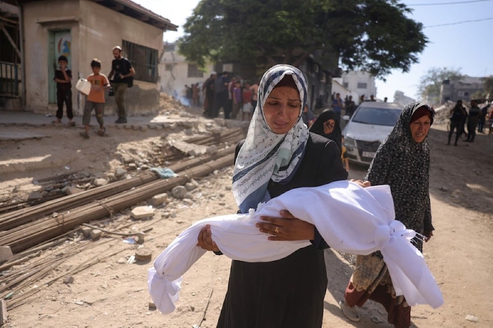 امرأة فلسطينية تحمل جثمان طفل خارج مستشفى الشفاء استشهد بقصف للاحتلال الإسرائيلي في مدينة غزة، في 29 آب/أغسطس 2025 (أ ف ب)
