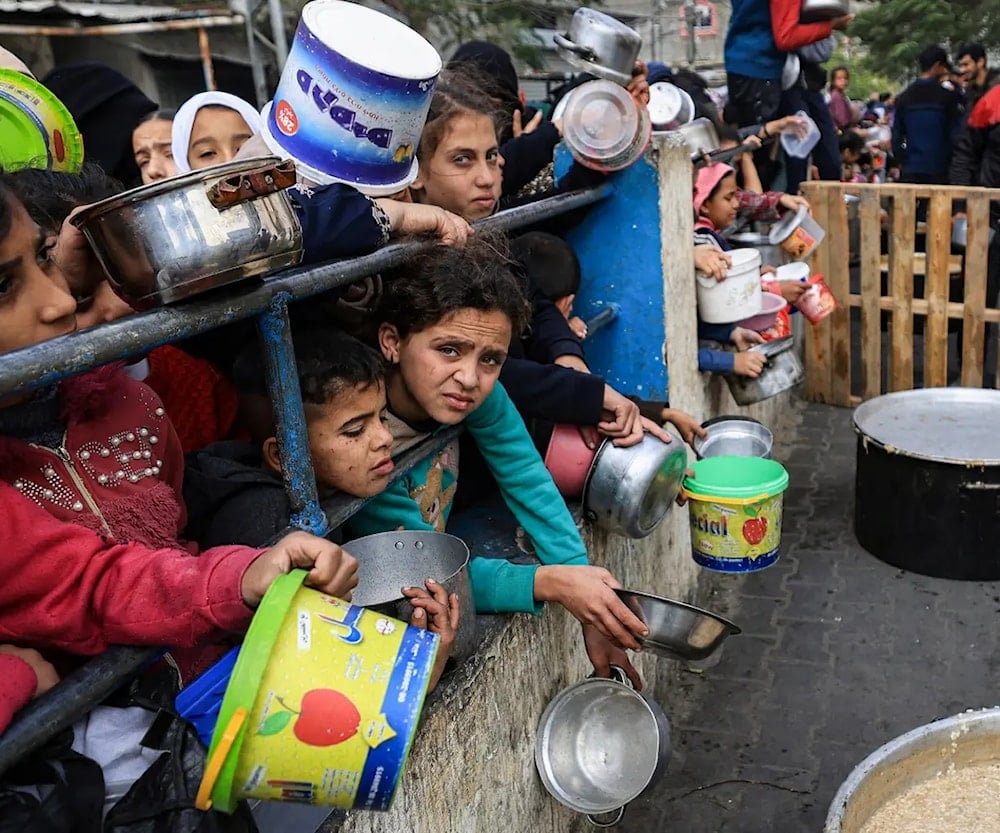 أطفال فلسطينيون ينتظرون دورهم للحصول على الطعام بعدما تفاقمت المجاعة في قطاع غزة بفعل الحصار الإسرائيلي (صورة أرشيفية)