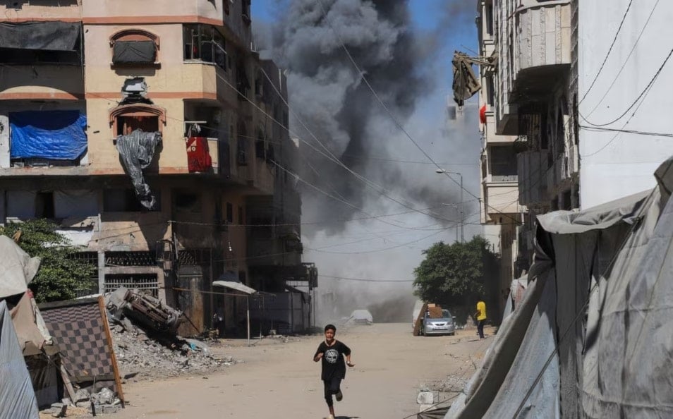 طفل يركض بينما يتصاعد الدخان من مبنى سكني كان يأوي فلسطينيين نازحين بعد أن ضربته غارة جوية إسرائيلية، في مدينة غزة. قطاع غزة. 12 أيلول/سبتمبر 2025. (رويترز)