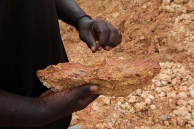 عامل منجم حرفي غير قانوني يتفقد صخرة محفورة بحثًا عن آثار الذهب في غانا 2024 (رويترز)
