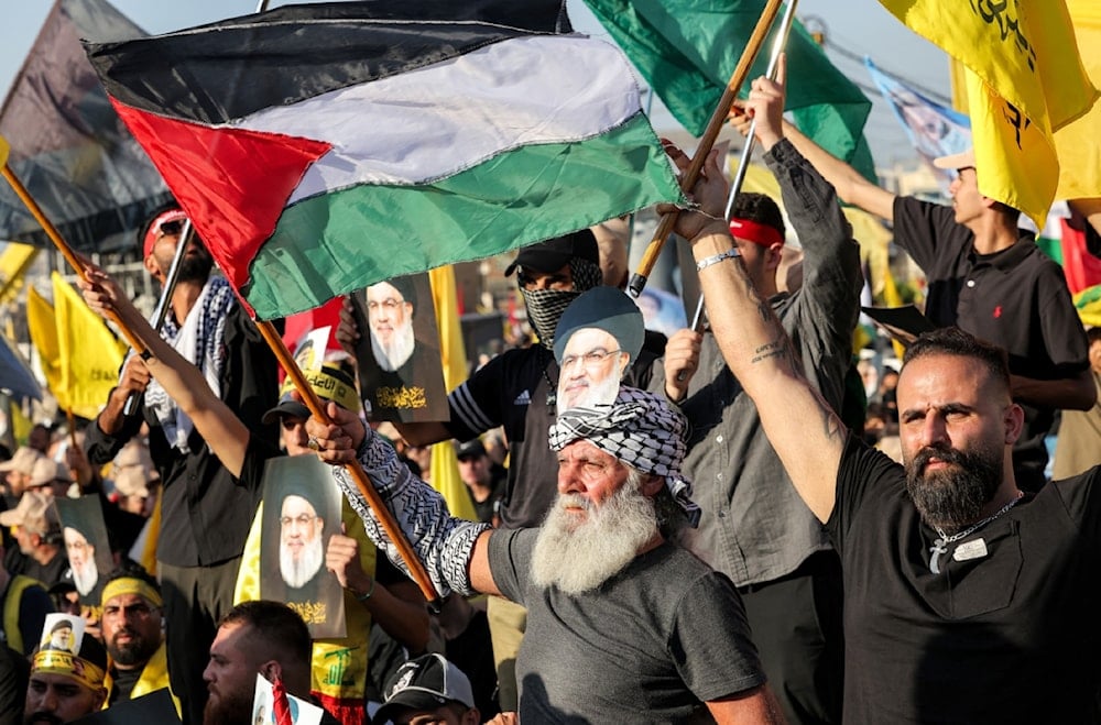 متظاهرون يلوحون بأعلام فلسطين في أثناء حضورهم حفلاً لإحياء الذكرى السنوية الأولى لشهادة في الضاحية الجنوبية لبيروت (أ ف ب)