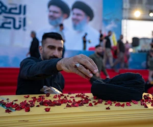 رجل عراقي يضع الزهور على نعشٍ رمزي لإحياء الذكرى السنوية الأولى لشهادة حسن نصر الله، في ساحة التحرير في بغداد رجل عراقي يضع الزهور على نعشٍ رمزي لإحياء الذكرى السنوية الأولى لشهادة حسن نصر الله، في ساحة التحرير في بغداد