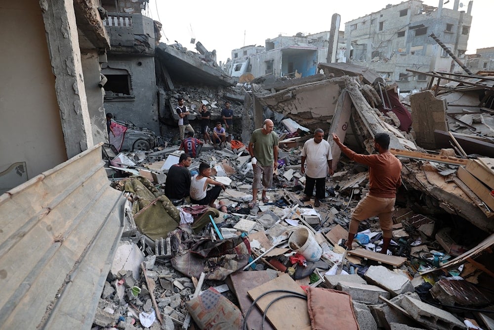 فلسطينيون على أنقاض مبنى دمّرته غارة إسرائيلية في مخيم النصيرات وسط قطاع غزة (أ ف ب)