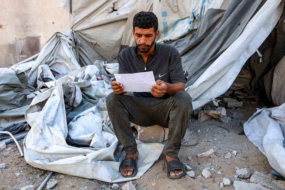فلسطيني يقرأ أحد المنشورات التي ألقاها الاحتلال الإسرائيلي على مدينة غزة، والتي تحث على إخلاء جنوبها باتجاه المواصي، في 9 أيلول/سبتمبر 2025 (أ ف ب)